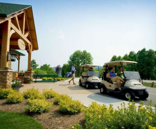 The image shows people at a golf course entrance, two golf carts with passengers, surrounded by greenery and a wooden building structure.
