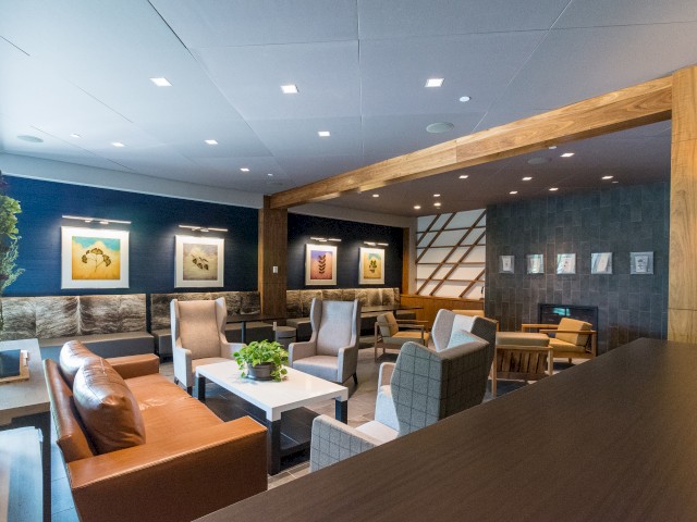 Picture shows lobby area for River Fox Restaurant and Bar, a modern lounge with comfortable seating areas. There is modern artwork on the walls, a mix of sofas and chairs, and wooden beams accent the ceiling.