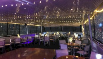 An elegantly decorated event space with string lights, tables, and chairs arranged for a gathering or celebration.