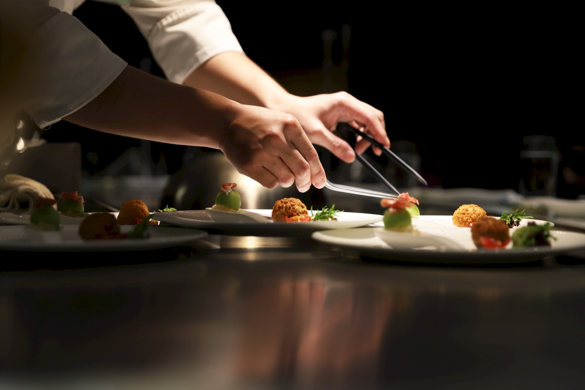 Chef's hand meticulously and carefully preparing a dish