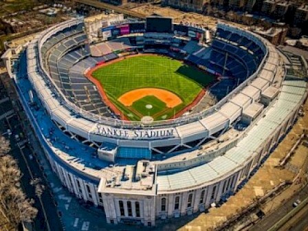 The image shows an aerial view of Yankee Stadium, with its baseball field in clear view and surrounding seating areas.