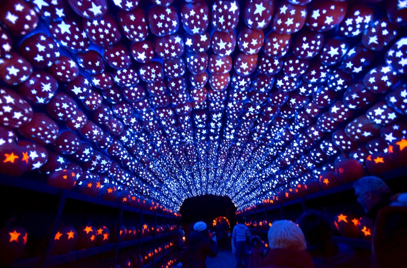 A tunnel illuminated with blue lights and star-patterned lanterns overhead, with people walking through.